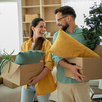 couple smiling and holding moving boxes