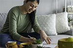 woman sitting on couch writing on paper