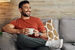 man with coffe cup sitting on a couch