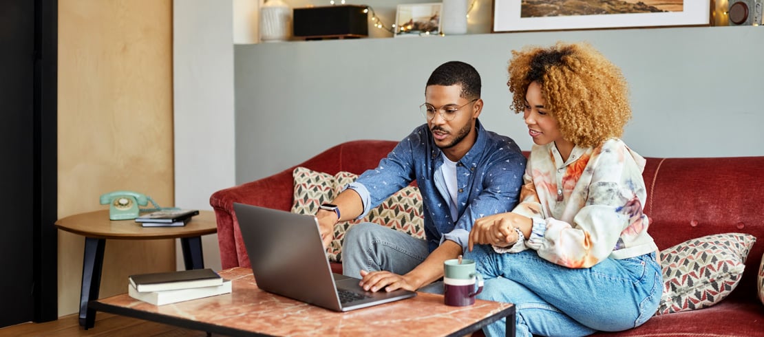 woman on sofa with credit card and laptop couple looking at a laptop together