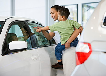 woman holding child while car shopping