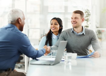 couple shaking hands across the table with an advisor