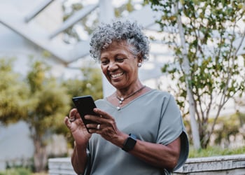 woman smiling while looking at her smartphone