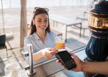 woman paying for drink by tapping debit card