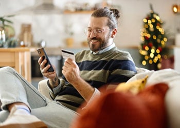 man looking at mobile phone and holding credit card