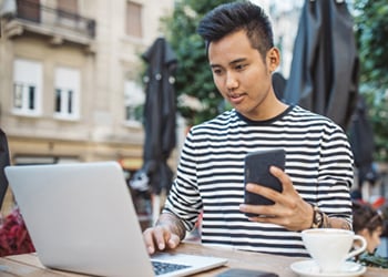 man lholding cell phone and working on laptop