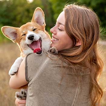 smiling woman holding corgi