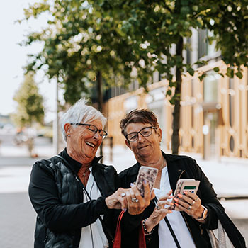 two women smiling and looking at phones