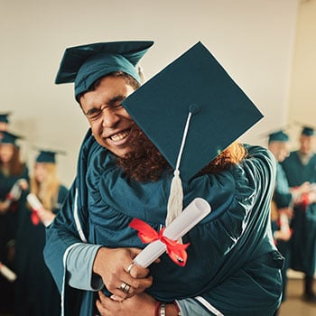 two graduates in cap and gown hugging