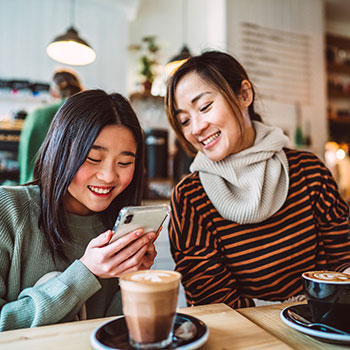 mother and daughter at coffee shop looking at phone