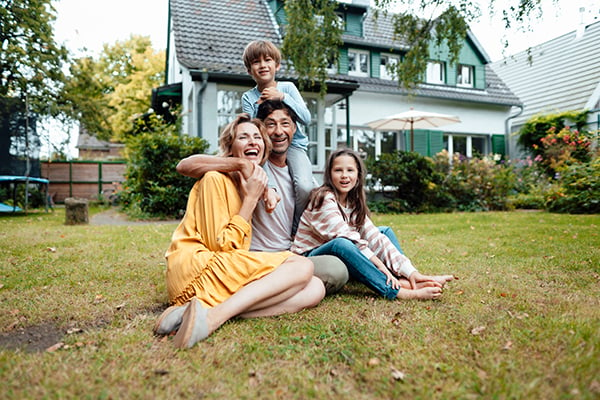 family sitting outside of new house