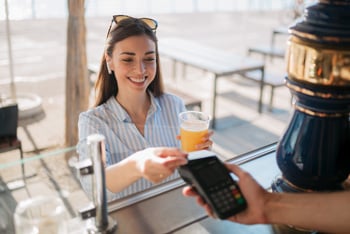 woman paying for drink by tapping debit card