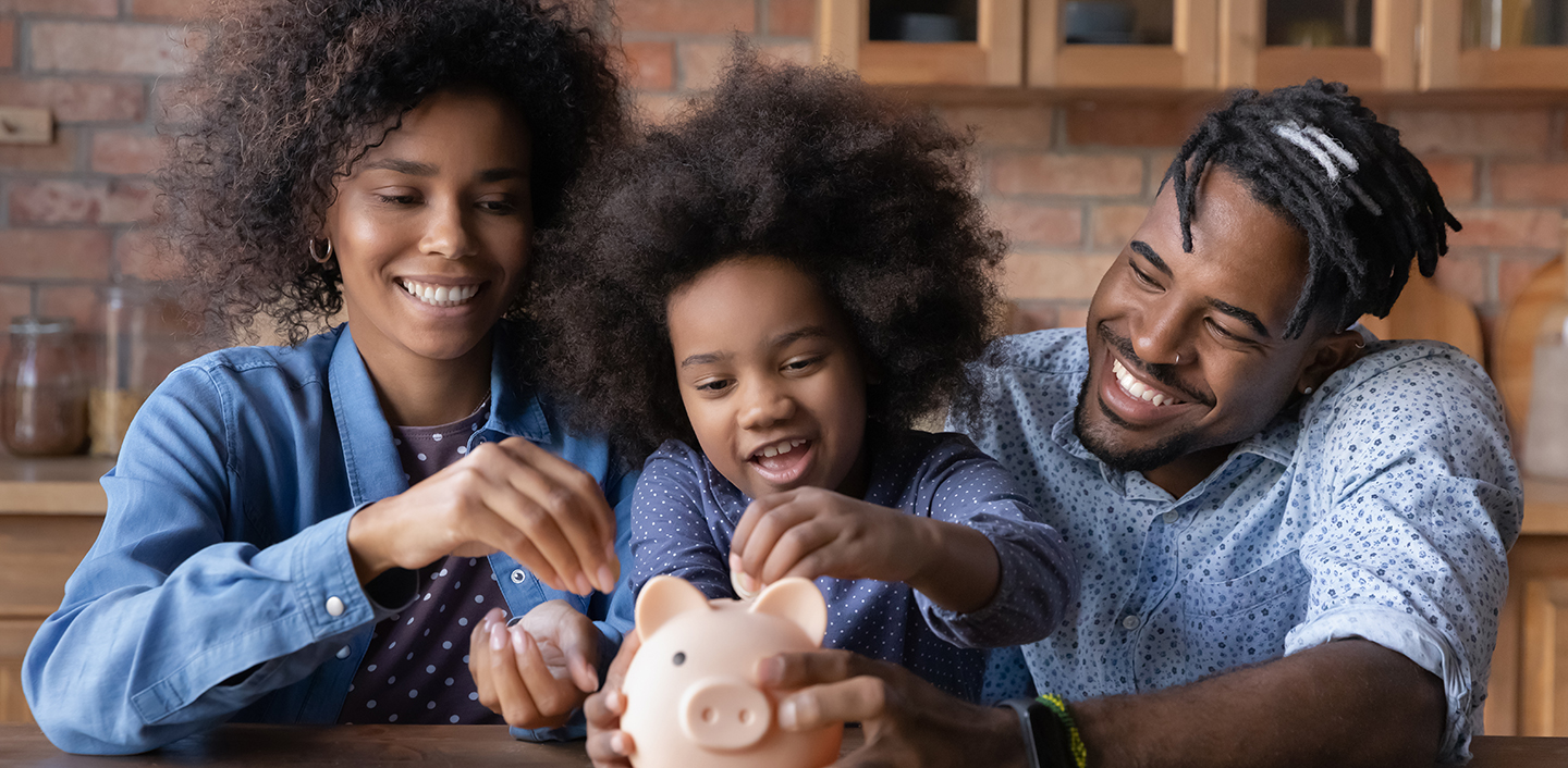 parents with young child adding money to piggy bank